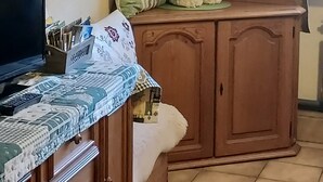 A room with a wooden cabinet, a television, and a table with a tablecloth.