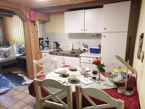 A cozy kitchen with a dining table set for two, a coffee maker, and a kettle.