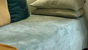 A bed with a grey blanket, two pillows (one beige, one green), and a wall-mounted light. - Elegant  peaceful flat with A/C  and all modern appliance in San Frediano (Florence)