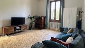 A living room with a sofa, TV, wooden cabinet, and a plant. - Elegant  peaceful flat with A/C  and all modern appliance in San Frediano (Florence)