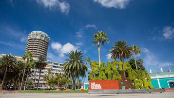 A hotel with a tall cylindrical tower, palm trees, and a sign that reads "Las Palmas de Gran Canaria".