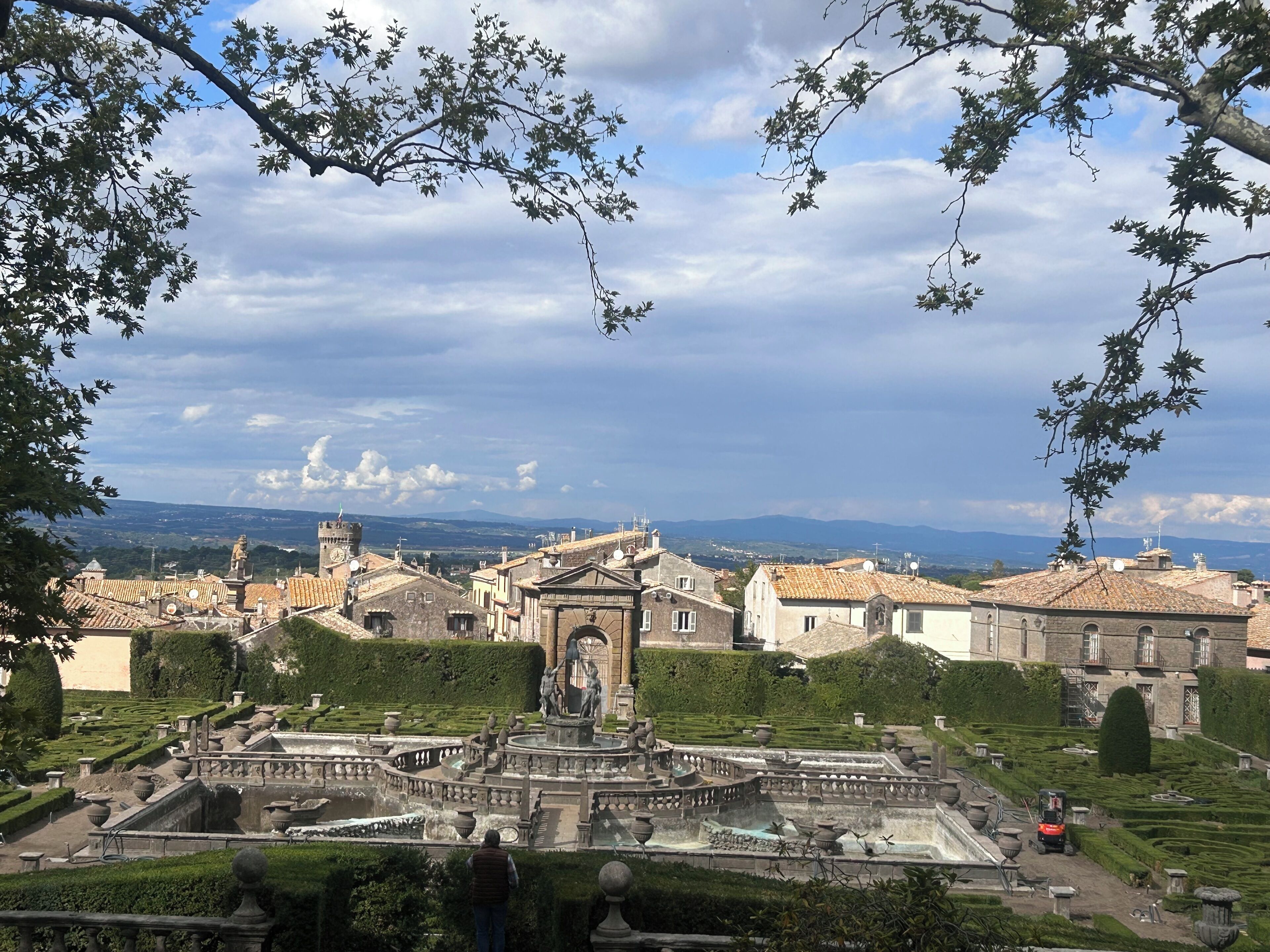 Un jardin historique doté d’une fontaine centrale, de haies parfaitement taillées et de statues classiques.