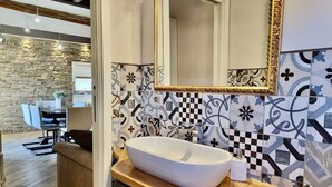 Un baño moderno con un lavabo blanco de diseño, una encimera de madera y baldosas estampadas.