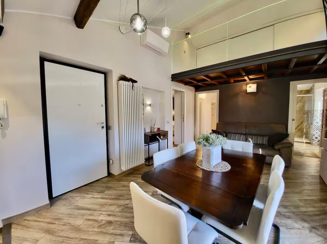 A modern dining area with a dark wooden table, white chairs, and a decorative centerpiece.