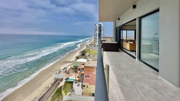 A balcony with a view of the beach and ocean.