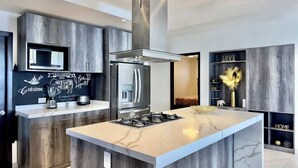 A modern kitchen with a central island, stainless steel appliances, and a chalkboard with writing.