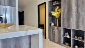 A modern kitchen with a marble countertop, grey cabinetry, and decorative items.