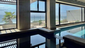 A modern interior with large windows overlooking a pool and the ocean.