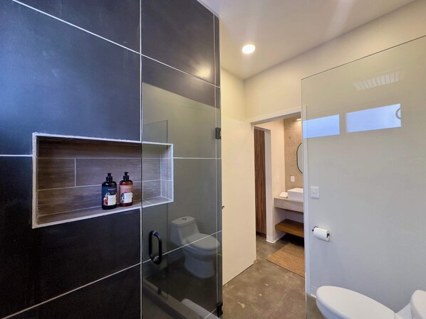 Un baño moderno con cabina de ducha de vidrio, inodoro y zona de lavabo.