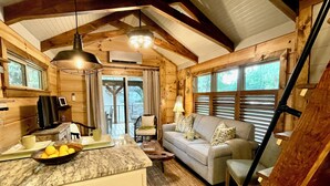 L’intérieur d’un chalet accueillant, avec un coin cuisine, un canapé et une table à manger.