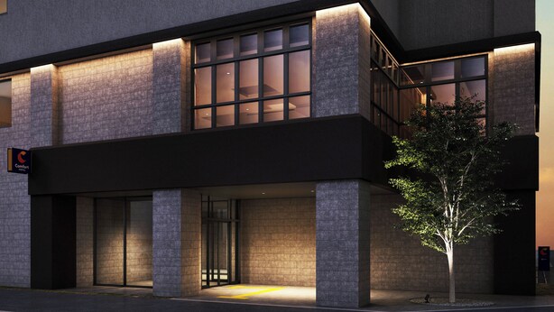 Un hôtel moderne doté d’une entrée imposante, de grandes fenêtres et d’une façade bien éclairée.