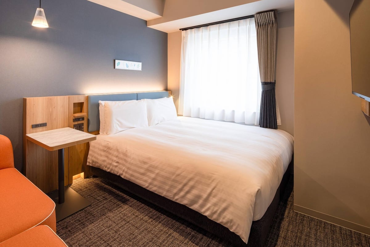 Een hotelkamer met een bed, nachtkastje, bureau en stoel.