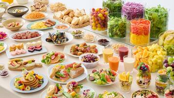 A variety of food and drink items on a table, including salads, sandwiches, and fruit.
