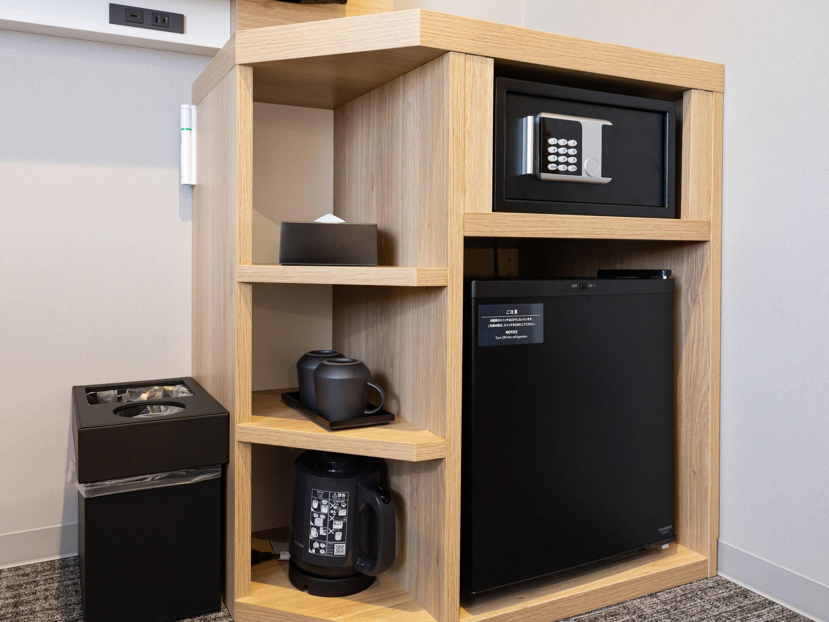 Eine kleine Küchenzeile mit einem schwarzen Kühlschrank, einer Kaffeemaschine und einer Mikrowelle.