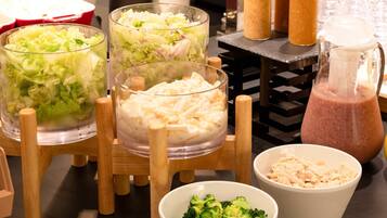 A buffet table with various food items including coleslaw, macaroni salad, and a pink smoothie.