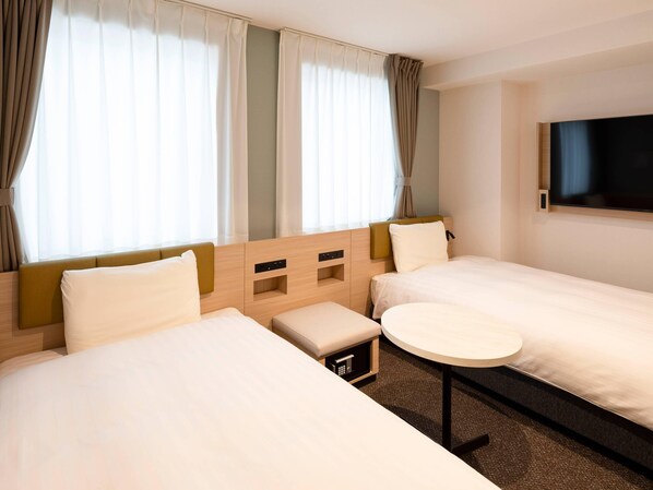 A hotel room with two beds, a small table, and a TV on the wall. - Comfort Hotel Mito (Mito)