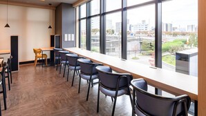 A modern conference room with a long table and chairs, large windows with a city view, and a wooden accent wall. - Comfort Hotel Mito (Mito)