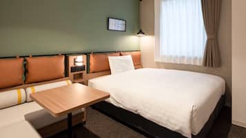 A hotel room with a bed, a sofa, a small table, a nightstand, and a window with curtains.