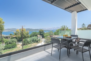 A balcony with a table and chairs, overlooking a scenic view of mountains and a body of water.