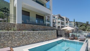 Et moderne hotel med swimmingpool, stenvæg og liggestole.