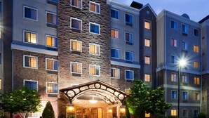 Un hotel de varios pisos con fachada de piedra, varios balcones y una entrada bien iluminada.
