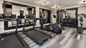 Un gimnasio con cintas de correr, elípticas y equipo de levantamiento de pesas.