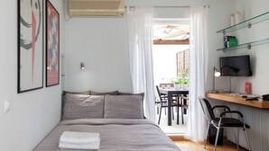 Une chambre à coucher avec un lit, un bureau avec un ordinateur, une chaise et un téléviseur.