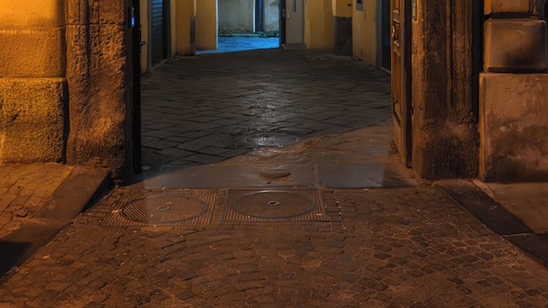 Un pasillo con una entrada arqueada, suelo de baldosas y un tragaluz en el techo.