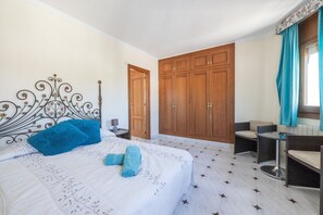 Une chambre comprenant un lit, une armoire, un coin salon et une petite table.