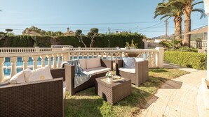 An outdoor seating area with wicker furniture, a small table with a flower vase, and a view of the sea. - Holiday Home 'Paraiso Para 4' with Shared Pool, Wi-Fi and Air Conditioning (Miami Platja)