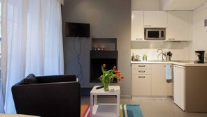 Una sala de estar moderna con un sofá negro, una mesita auxiliar blanca con un jarrón de tulipanes, y una alfombra colorida.