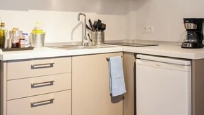 Una cocina compacta equipada con microondas, lavavajillas y fregadero.