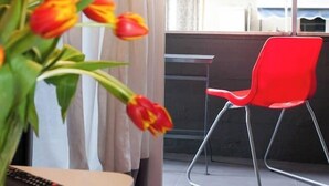 Una sala de estar moderna con un sillón rojo, un control remoto y un jarrón de tulipanes.