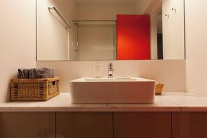 Ein Badezimmer mit Waschbecken, Spiegel und zwei Korbwannen auf der Ablagefläche.