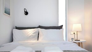 Un letto ben rifatto con lenzuola bianche e due asciugamani piegati ai piedi.