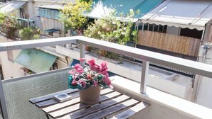 A balcony with a wooden table and bench, a potted plant, and a view of a swimming pool. - #AH31 Olive Studio (Athens)