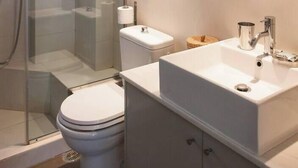 A modern bathroom with a glass-enclosed shower, a toilet, and a sink with a mirror above. - #AH31 Olive Studio (Athens)