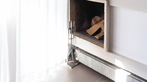 A modern living room with a fireplace, a framed picture on the wall, and a radiator below. - #AH31 Olive Studio (Athens)