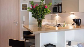 A modern kitchen with a wooden countertop, a vase with flowers, a microwave, and a coffee machine. - #AH31 Olive Studio (Athens)