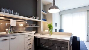 A modern kitchen with white cabinets, a built-in stove, and a dining area with a glass table and metal chairs.