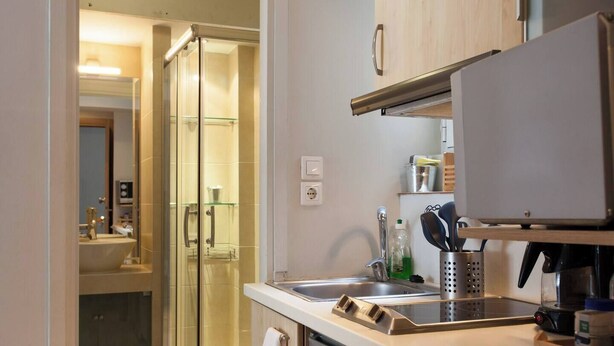 A compact kitchen with a sink, a coffee maker, and a glass shower enclosure. - #AH34 Beige Studio (Athens)