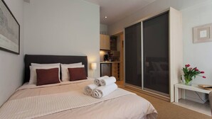 A modern bedroom with a large bed, a sliding glass door to a balcony, and a small table with a vase of flowers. - #AH34 Beige Studio (Athens)
