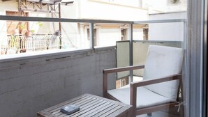 A balcony with a wooden table and a white cushioned chair. - #AH34 Beige Studio (Athens)