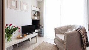 A modern living room with a flat-screen TV, a sofa, a coffee table, and a fireplace. - #AH34 Beige Studio (Athens)