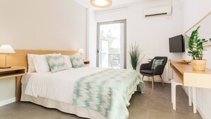 A modern hotel room with a bed, bedside lamps, a desk with a chair, a television, and a potted plant. - #FH10 New studio in Faliro (Paleo Faliro)