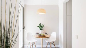 A dining area with a round table, two white chairs, a hanging light fixture, and a plant on the table. - #FH10 New studio in Faliro (Paleo Faliro)