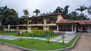A multi-story building with balconies, a parking area, and a small garden with plants. - Domus Hotel Núcleo Urbano de Carajás – Parauapebas (Parauapebas)