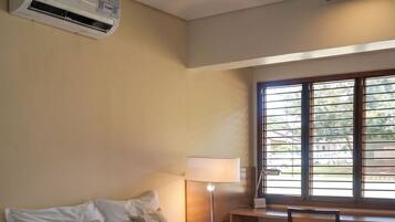 Una habitación de hotel con cama, escritorio, lámpara y ventana con persianas.