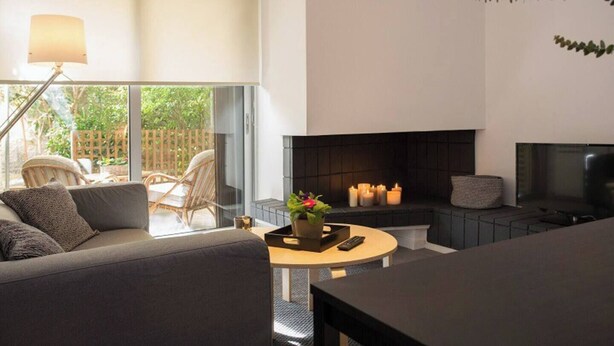 Una sala de estar moderna con un sofá, una mesa de centro, una chimenea y un televisor.