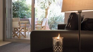 A room with a black sofa, a lamp, and a lit candle on a table. - #FH13 Garden level studio in Faliro (Paleo Faliro)